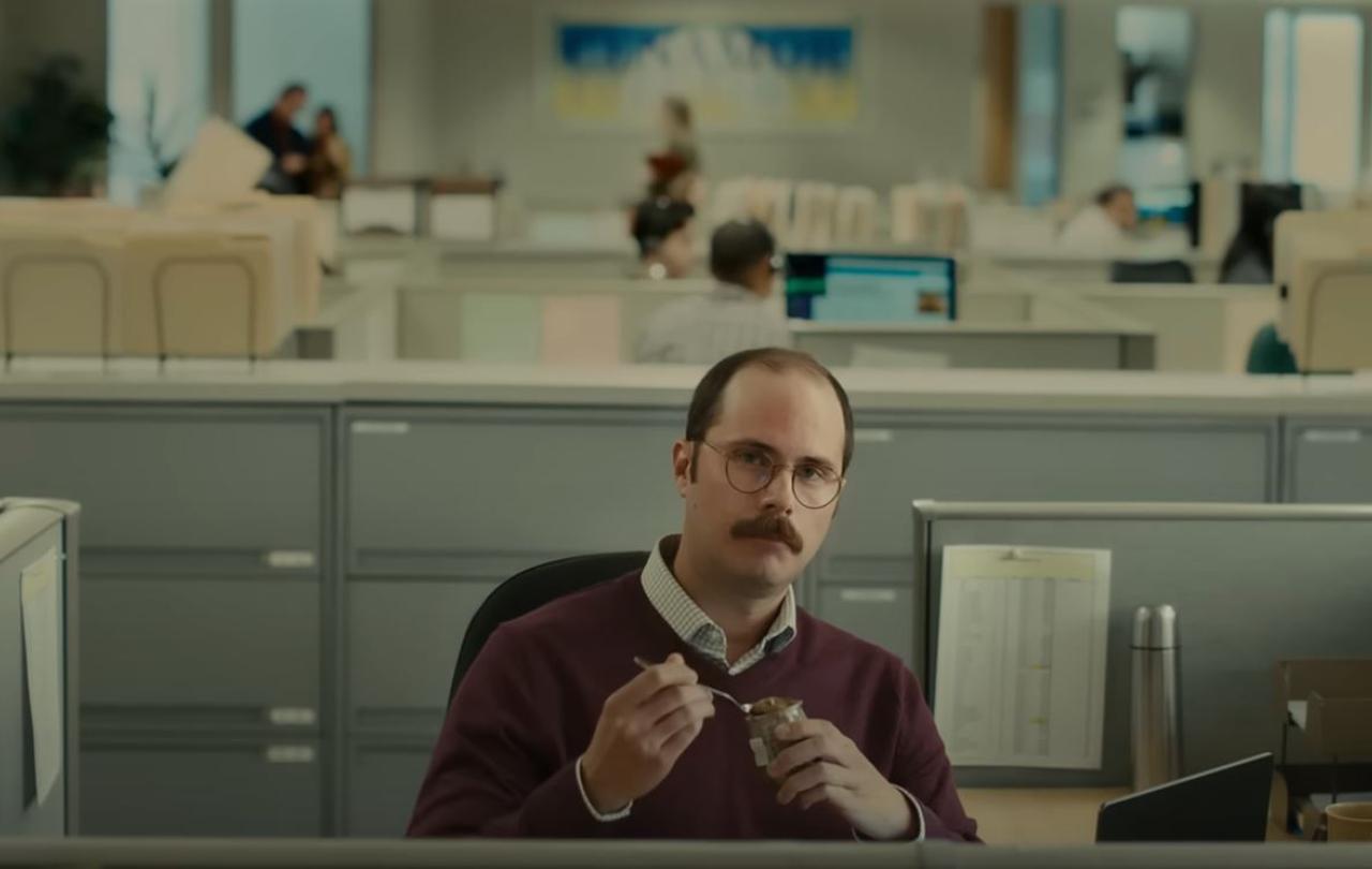 A worker at a desk sits back contemplating a situation
