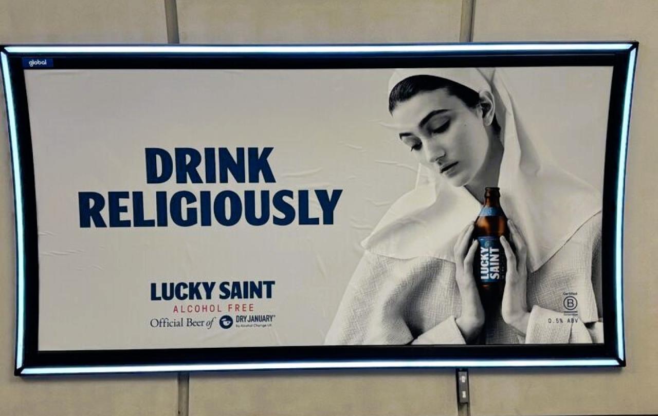 A subway billboard ad show a nun cradling a beer.