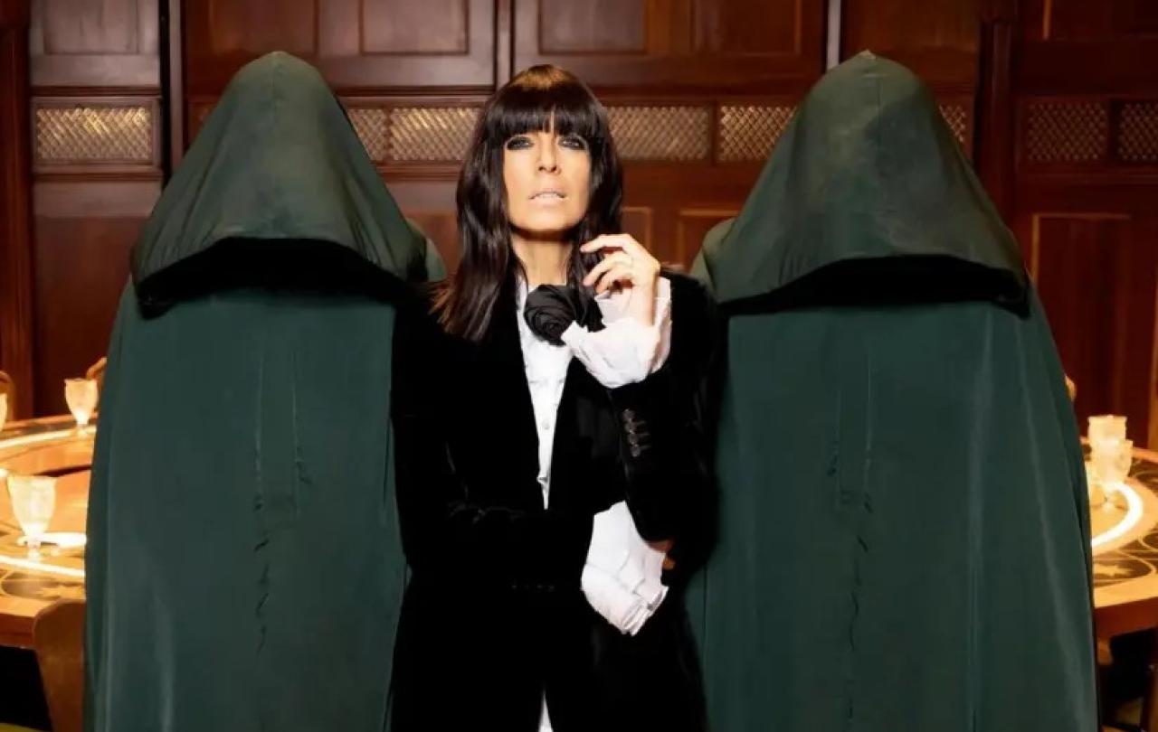 A TV show presenter looks imposing between two hooded figures.