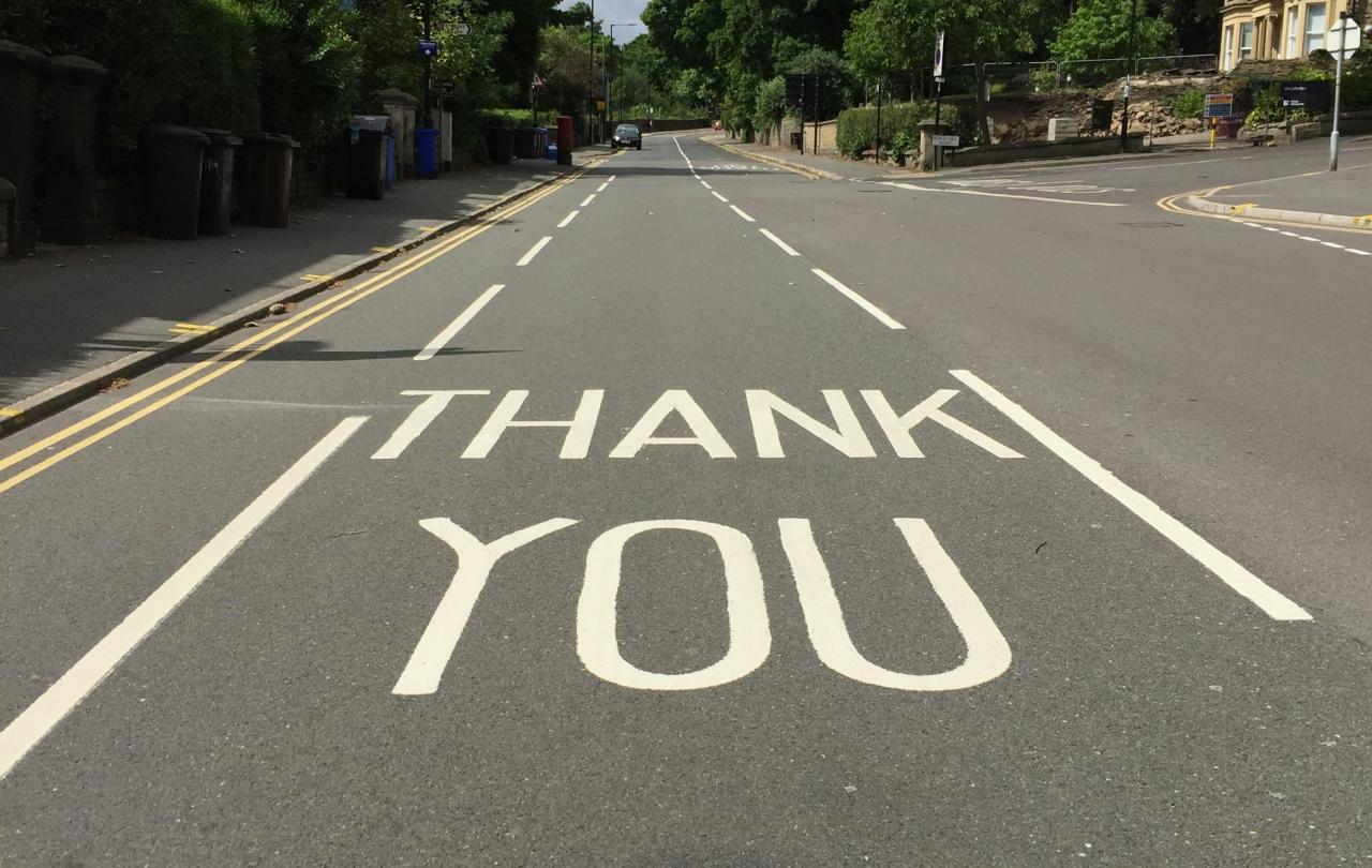 A  painted sign on a road reads 'THANK YOU'
