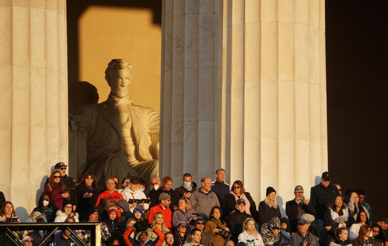 A crowd of people stand in the side steps of the Lincoln Memorial