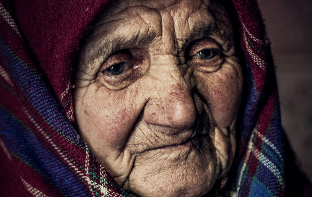An old woman wearing a shawl looks pensive.