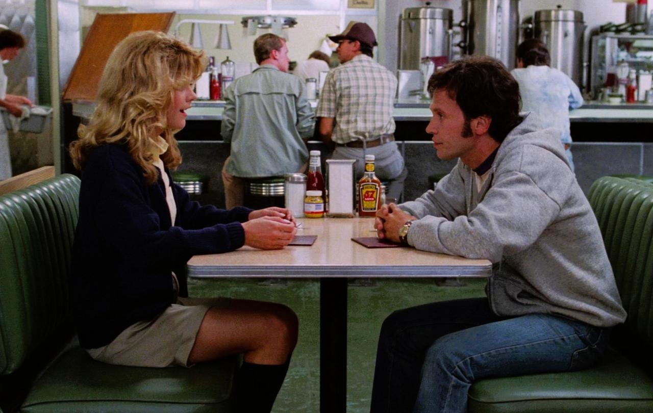 A couple sit at a table in a diner talking intensely.