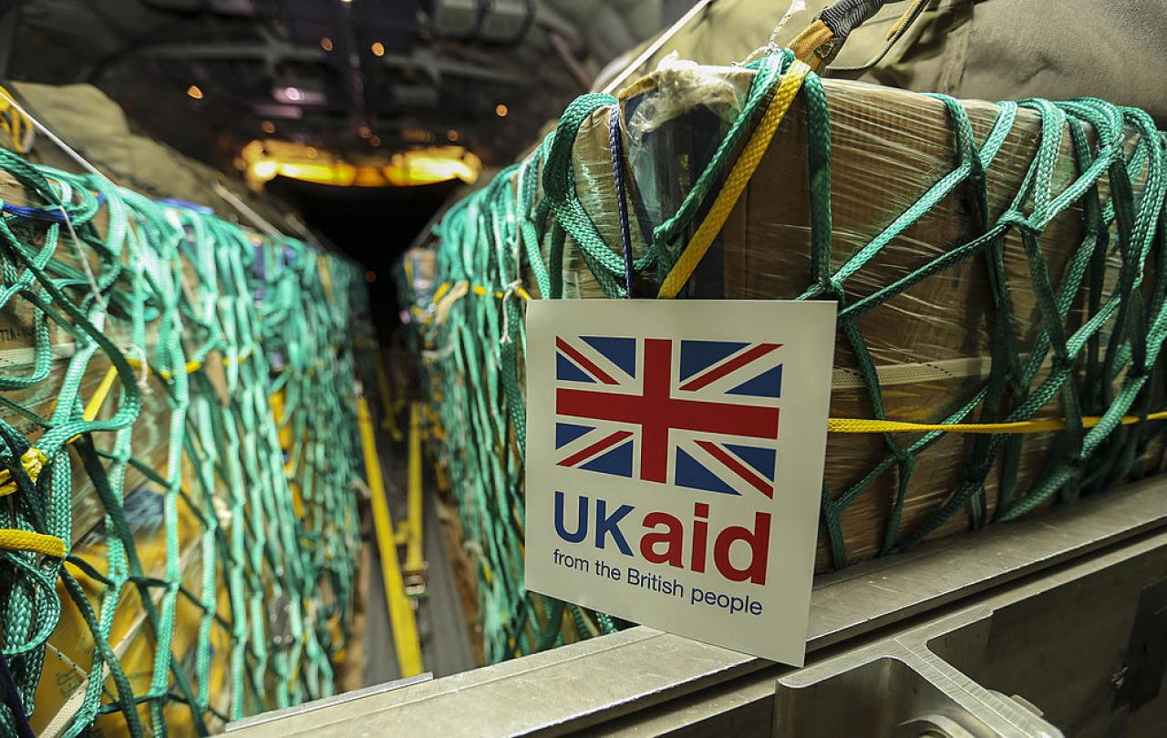 Cargo sits in nets inside a plane, a sign reads 'UK Aid'