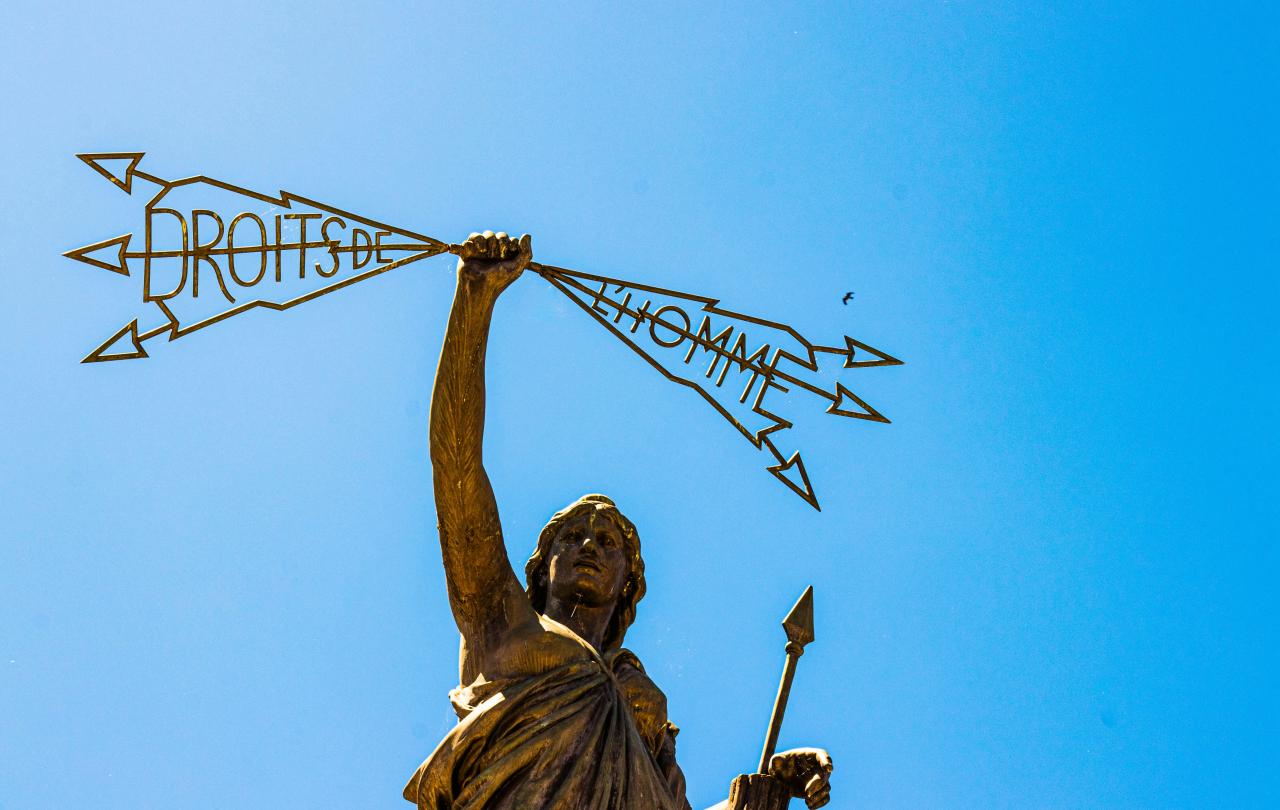 A statue of a woman holding a spear in one hand a lightening bolt in the others that reads: 'Droits de  l'homme'.