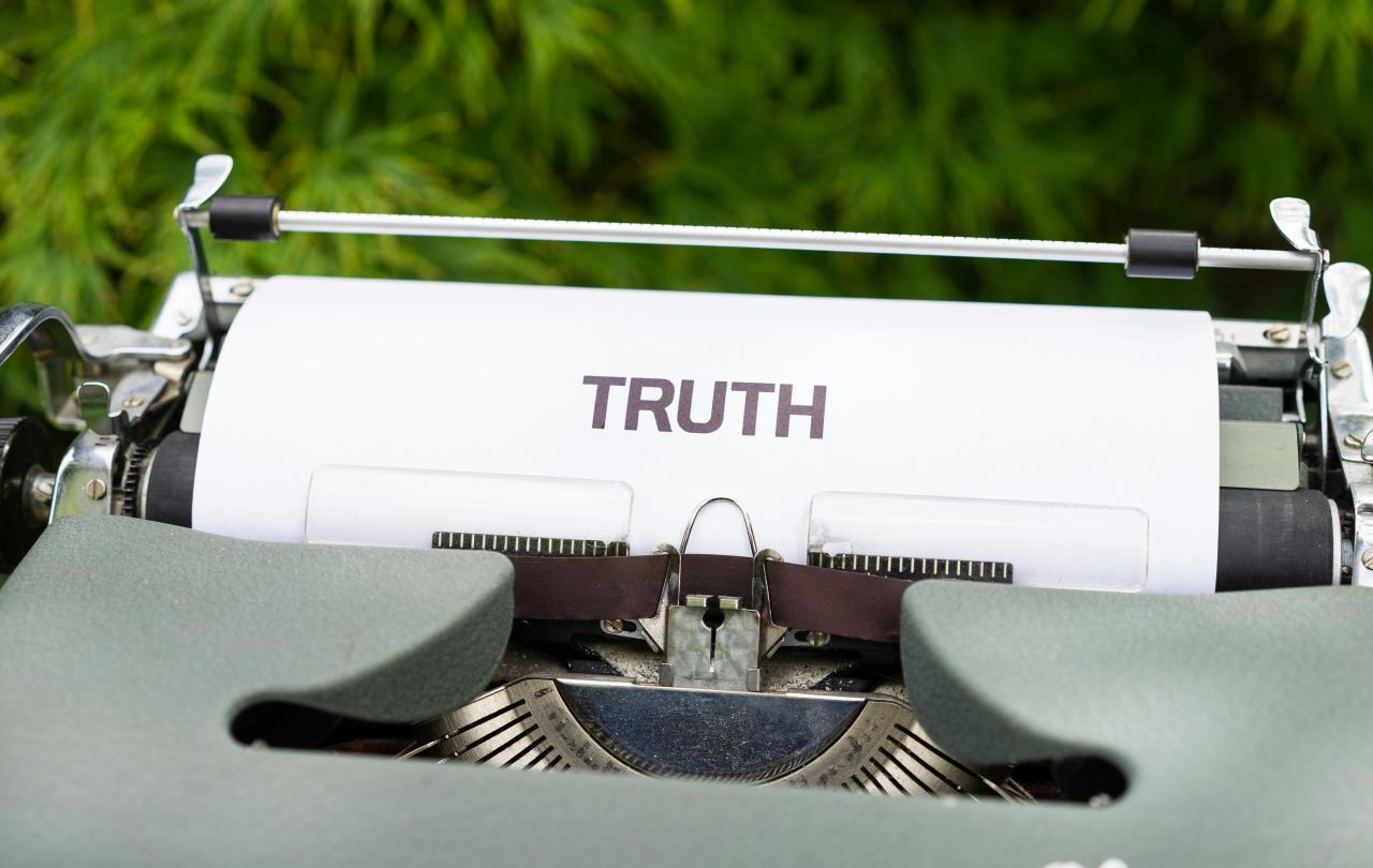 A typewriter holds a piece or paper reading 'truth'