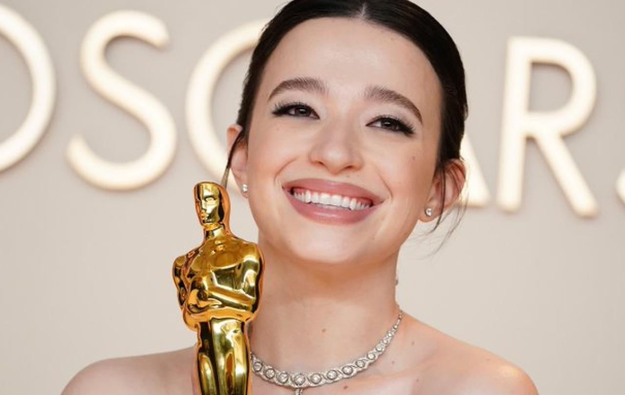 Mikey Madison, wearing a ball gown, clutches a golden Oscar statue.