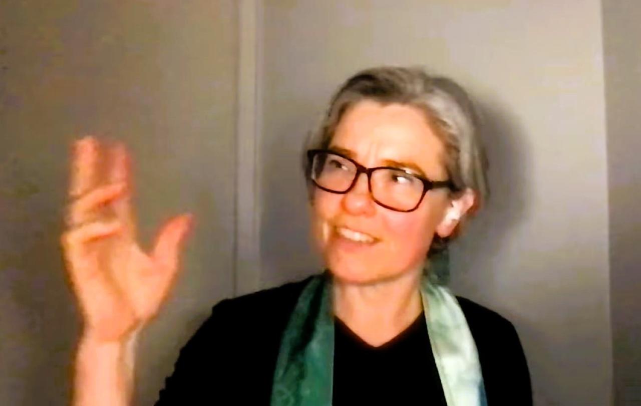 A podcast guest holds up her hand and looks at it while speaking.