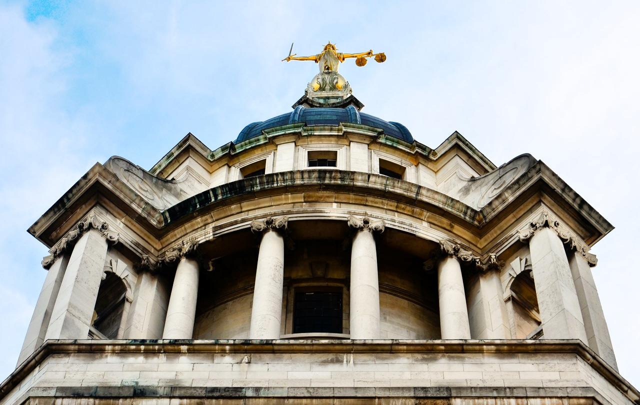 A classical court house with a statue on top of a dome.
