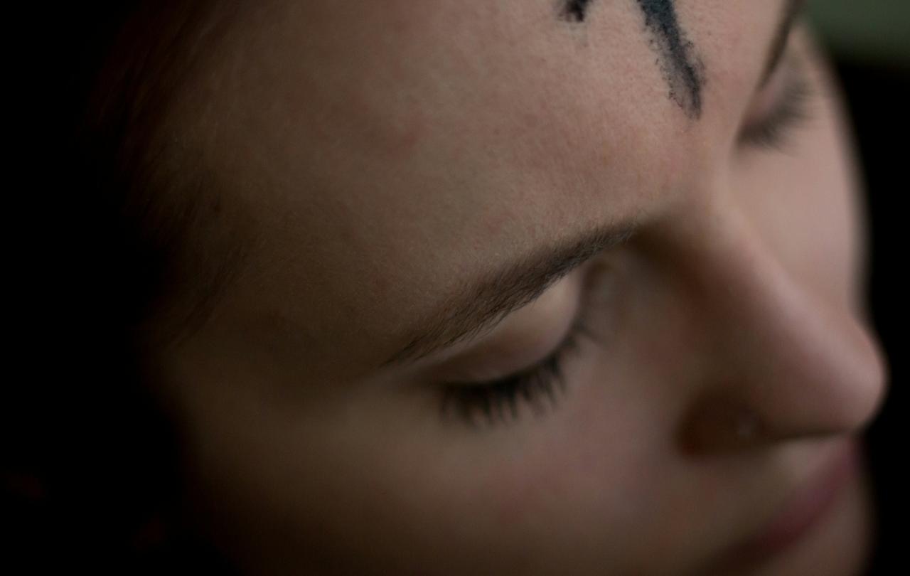 A close up of a forehead bearing an ash cross marked on it.