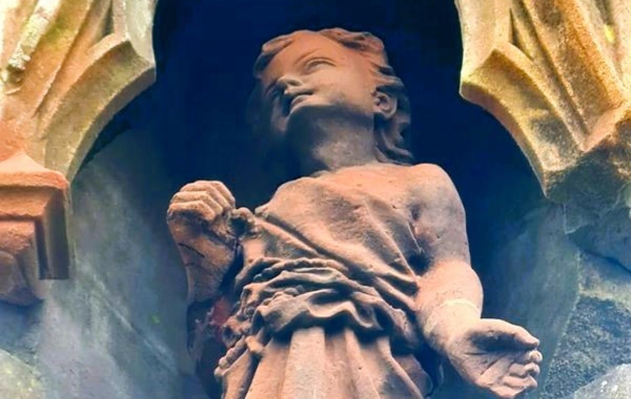 A red sandstone statue of Jesus as a child.