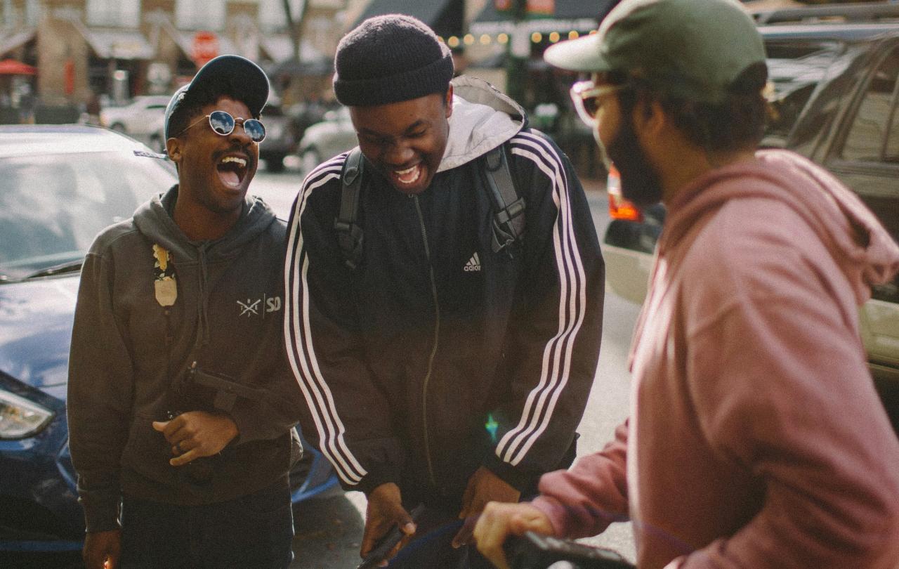 Three friends in the street laugh together.