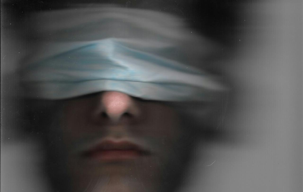 A blurred image of a blindfolded man.