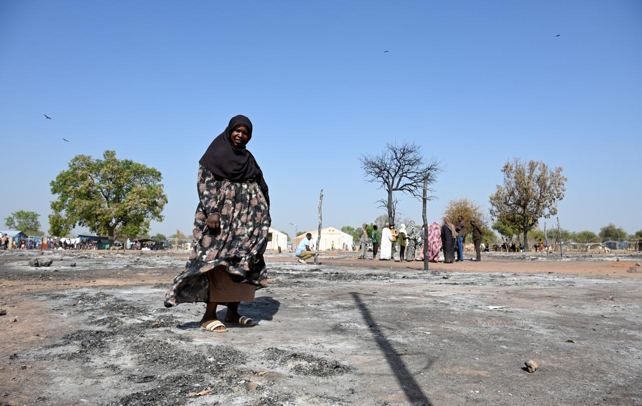 A Sudanese woman walks across the ashes of a burnt out street market.
