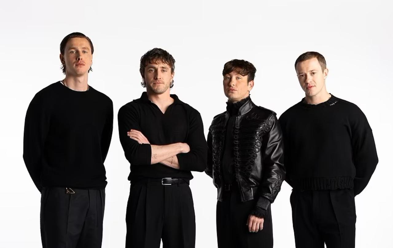 Four actors dressed in black stand together