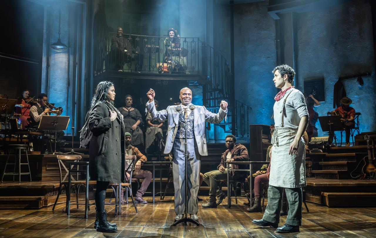 A theatrical staging shows a couple seperated by a man standing between them.