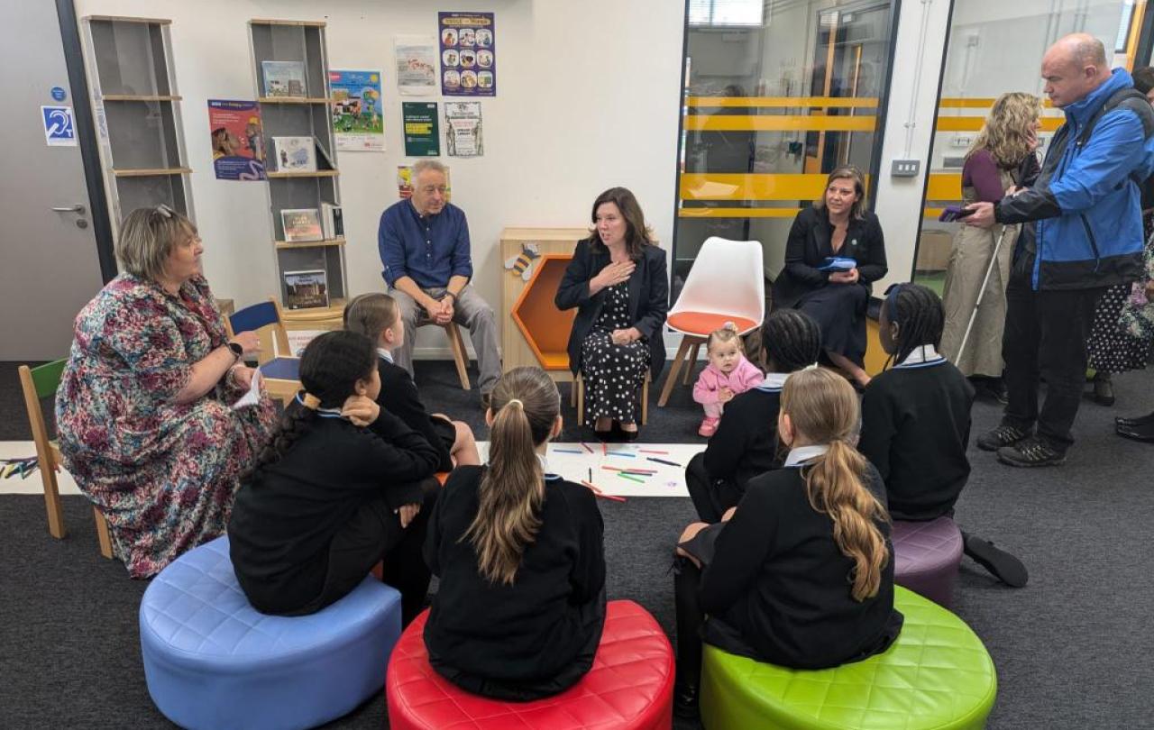 Children sit in a library listening to a story
