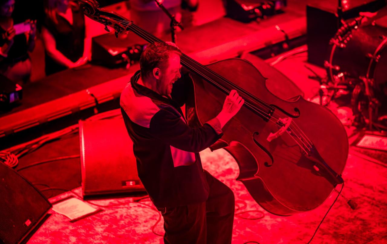 A bassist hauls a double bass of its base as he plays it.
