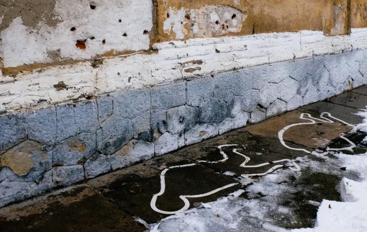 Bullet holes on a wall and white paint outlines mark the site of an execution