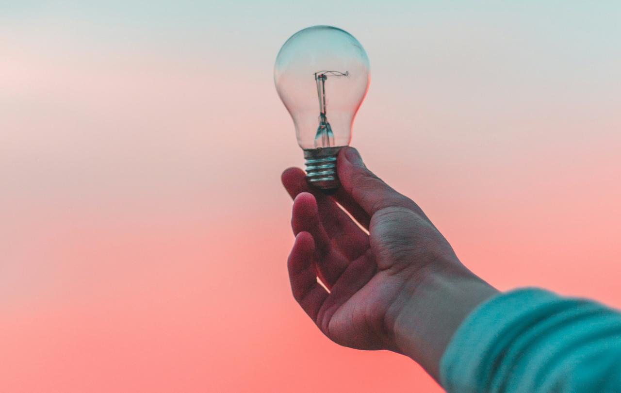 A light bulb is held up against a sunset.