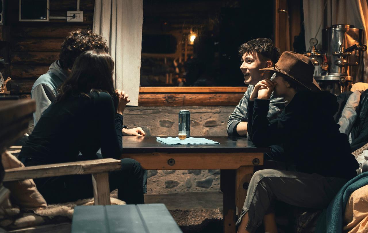 Four people sit round a pub table, some look animated, others pensive.