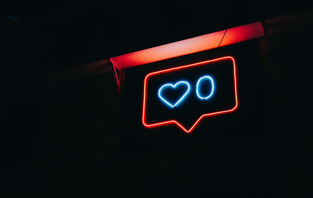 A neon sign depicts a message balloon with a heart symbol and a zero next to it.