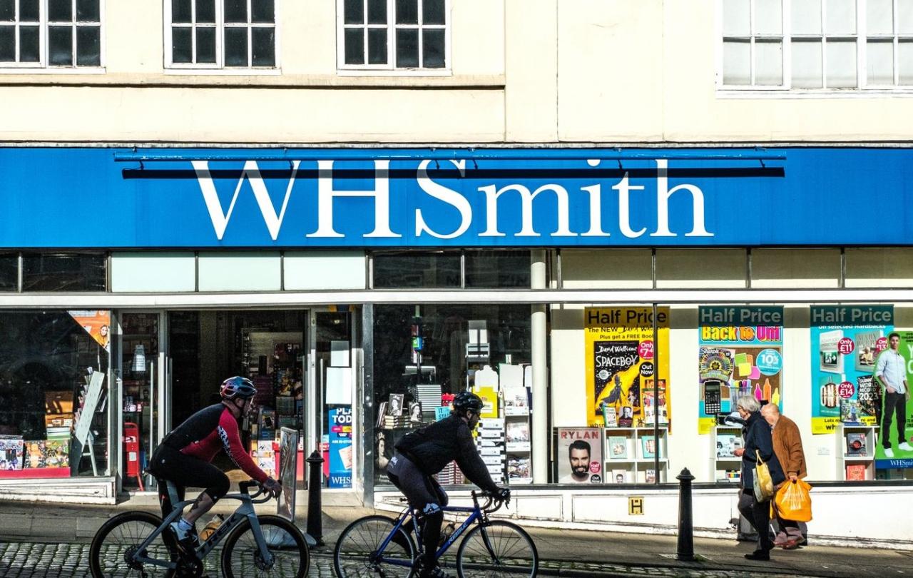 Cyclists and pedestrians pass in front of a WH Smith store front.