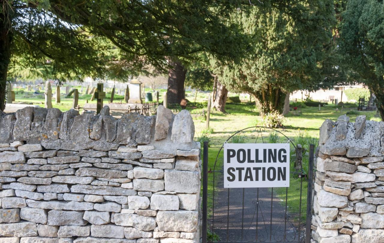 A gate to a churchyard displays a sign saying polling station.