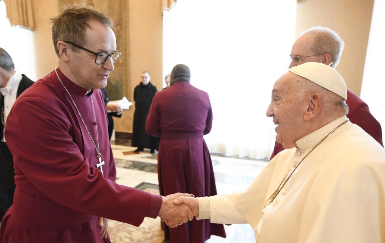 An Anglican bishop wearing purple shakes hands with the Pope.