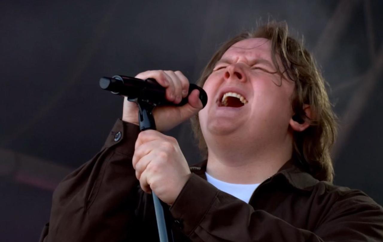 Lewis Capaldi sings with eyes closes, holding a mic and its stand