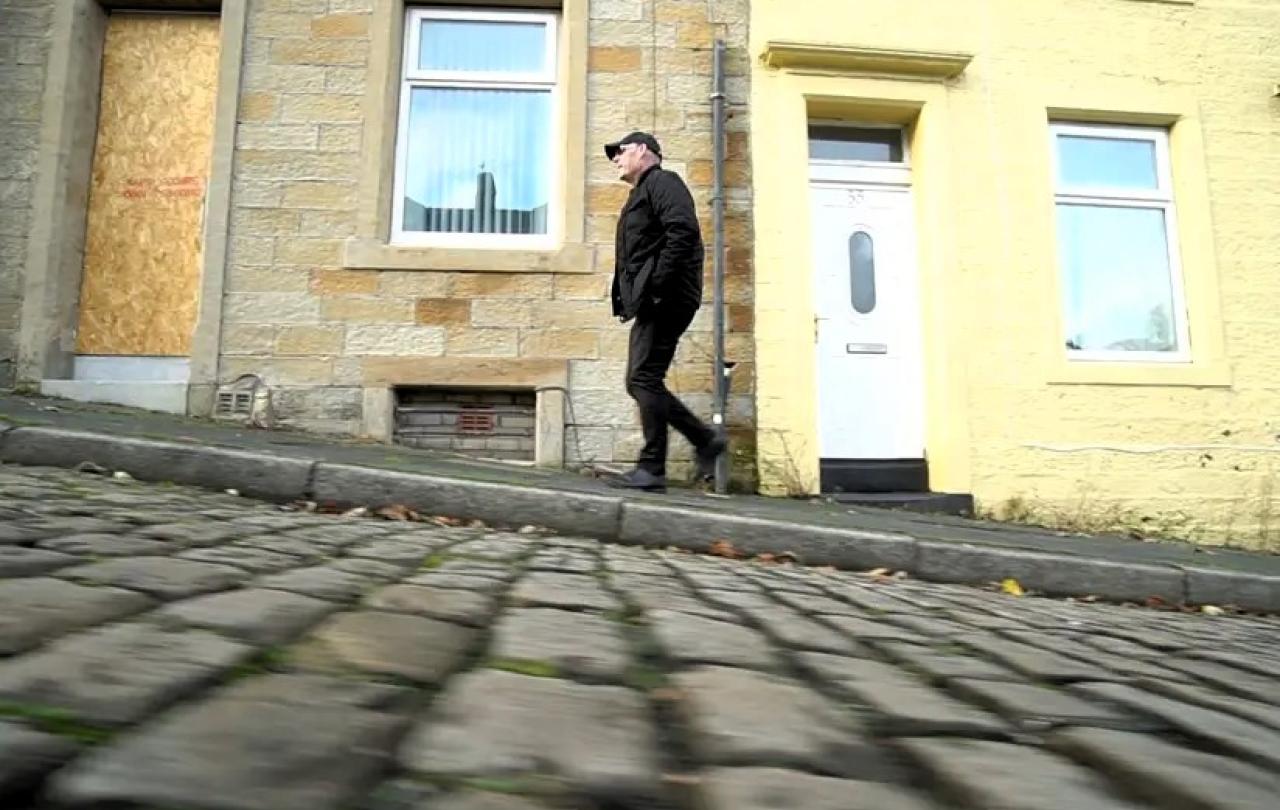 A man walks up a cobble street.