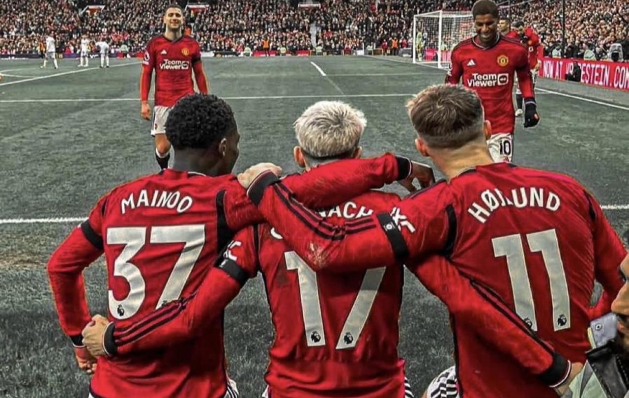 Three Manchester United footballers with their arms around each others backs.