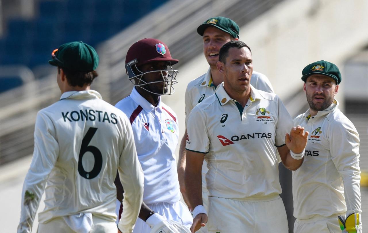 A cricket batsman surrounded by opposition players leaves the crease.