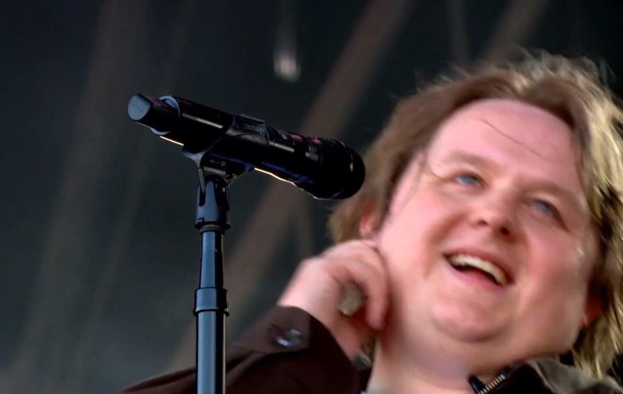 A singer leans back from the mic smiling