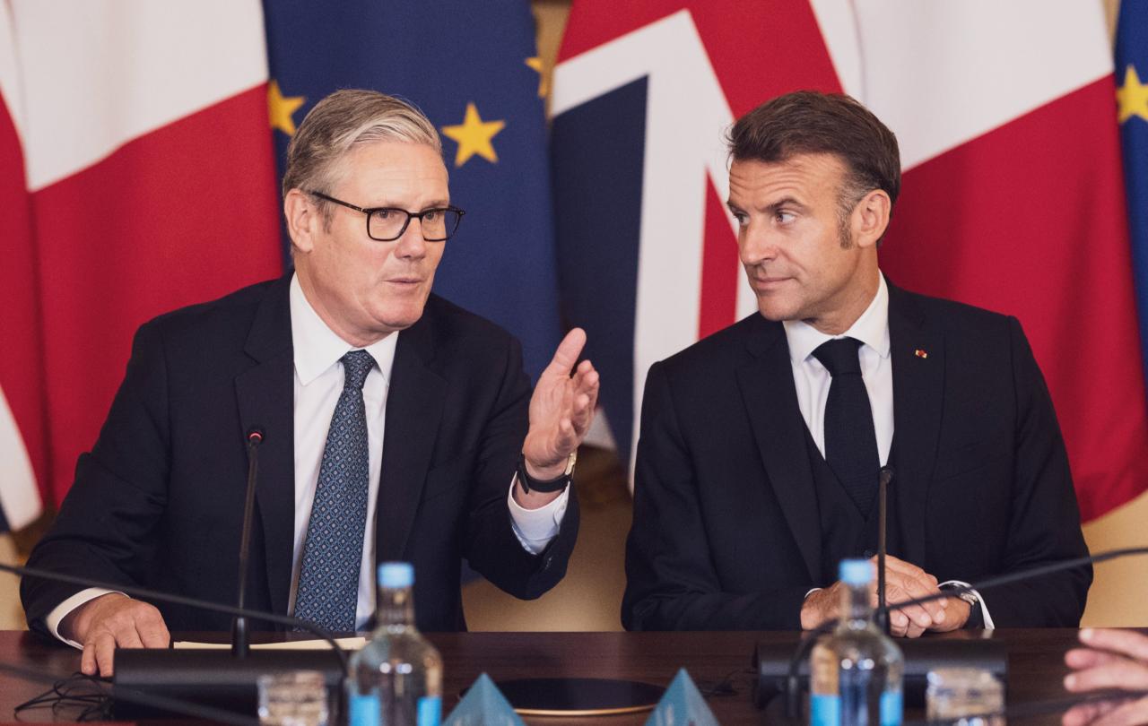 Keir Starmer and Emmanuel Macron in front of flags.