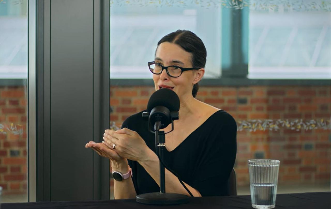 a woman speaks and gestures while recording a podcast