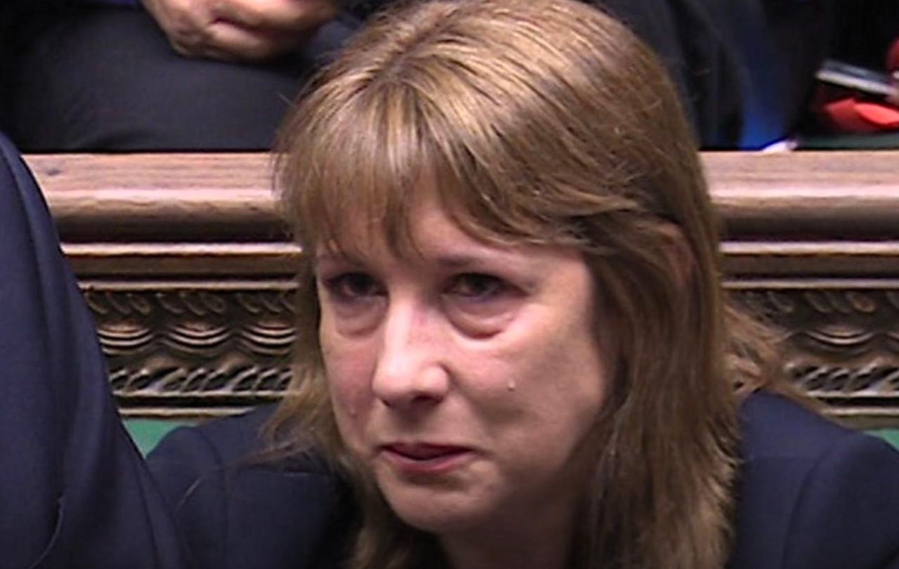A woman sits and holds back a tear.