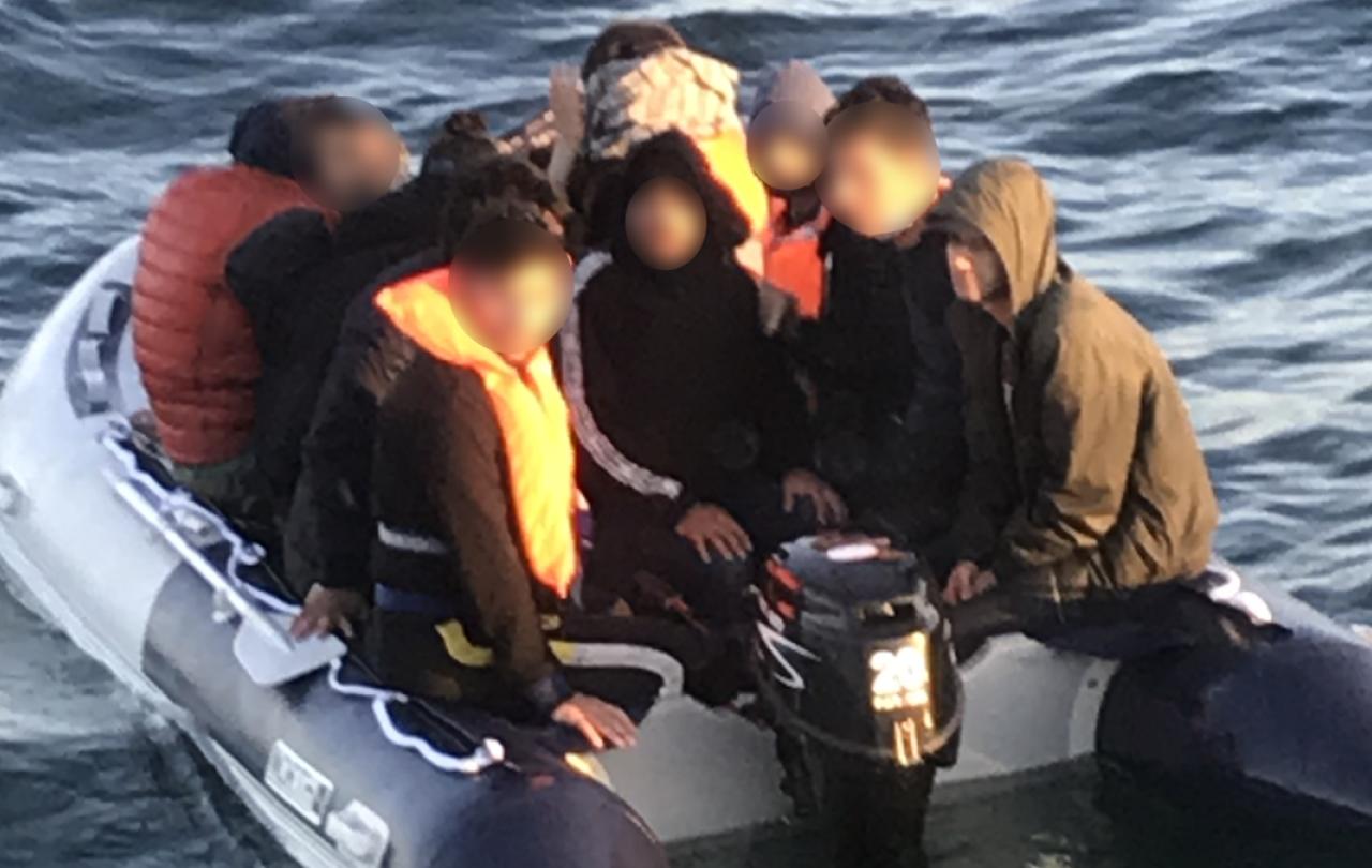 A people sumggler steers an overcrowded small boat.
