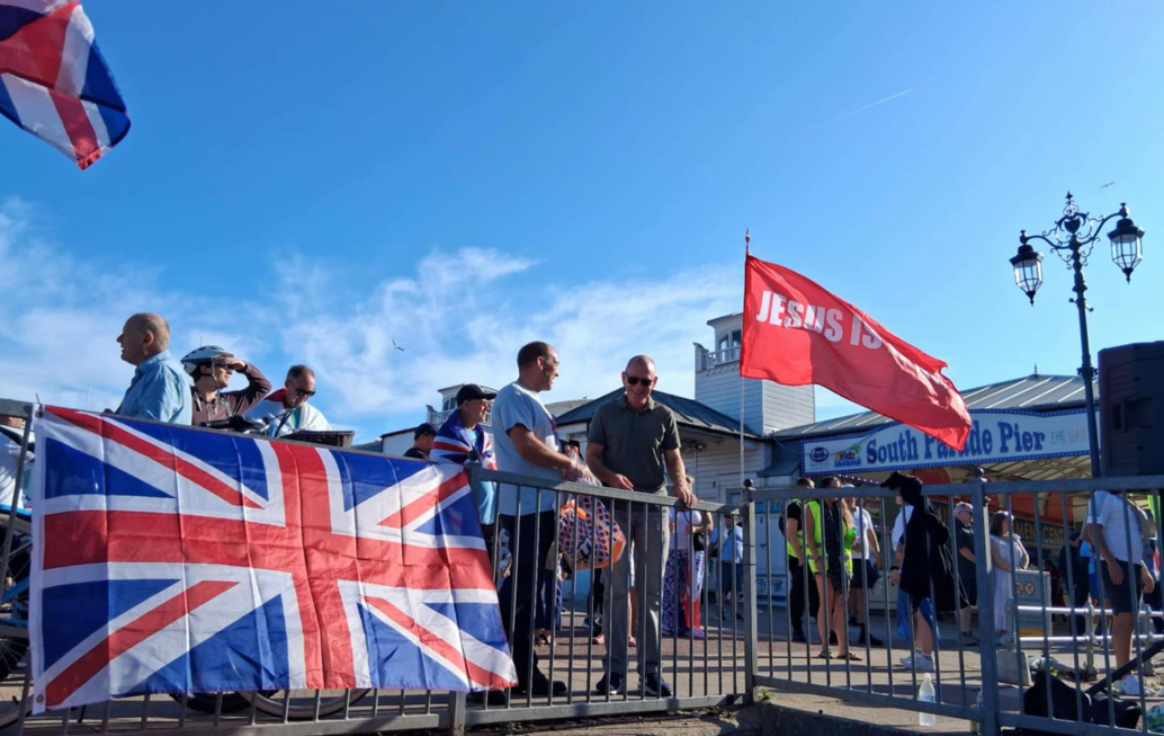 A Union Jack is draped over a railing, next to a red flag saying Jesus.