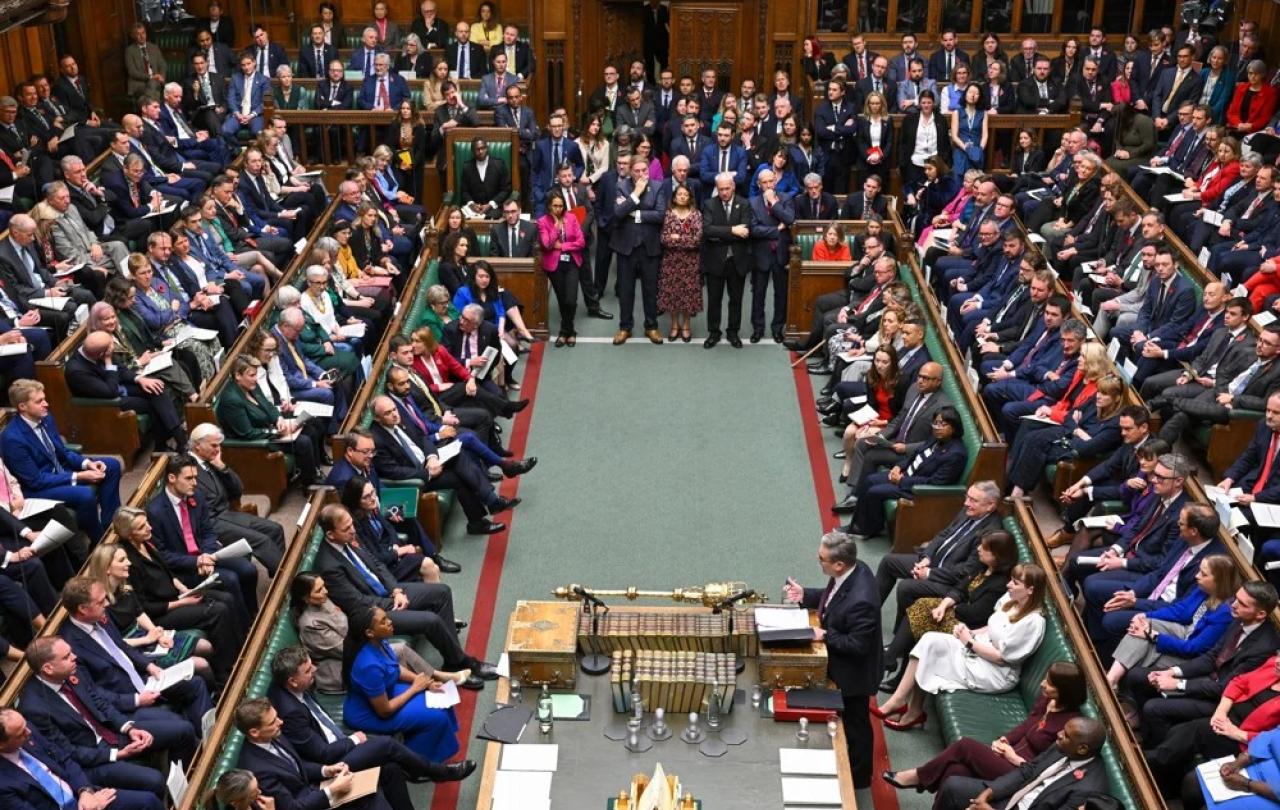 MPs sit and stand in a crowded parliament.