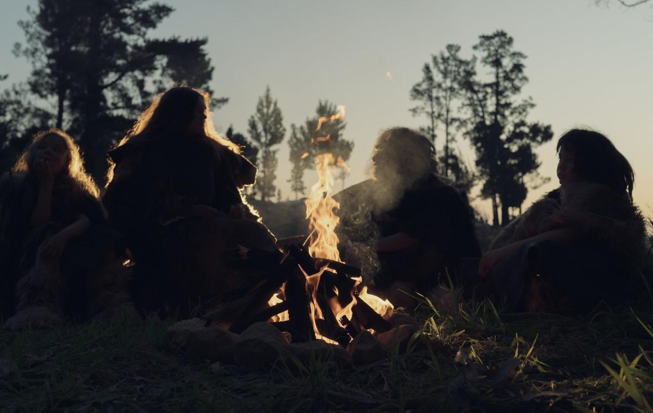 A re-enactment of an ancient 'caveman' family sitting around a camp fire.