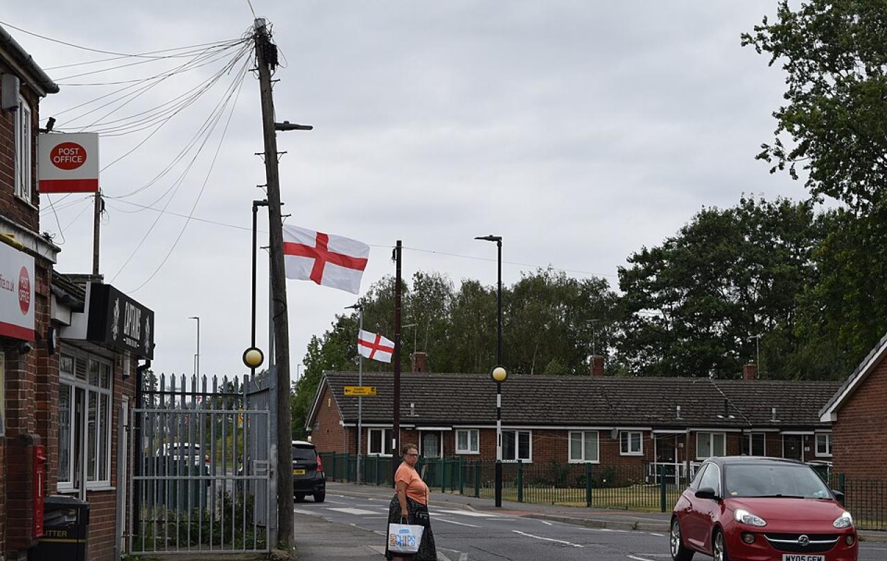 A suburban English street with St George's Cross flags on lamposts.