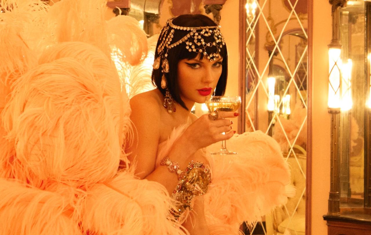 Taylor Swift, dressed as a showgirl, sips from a glass.