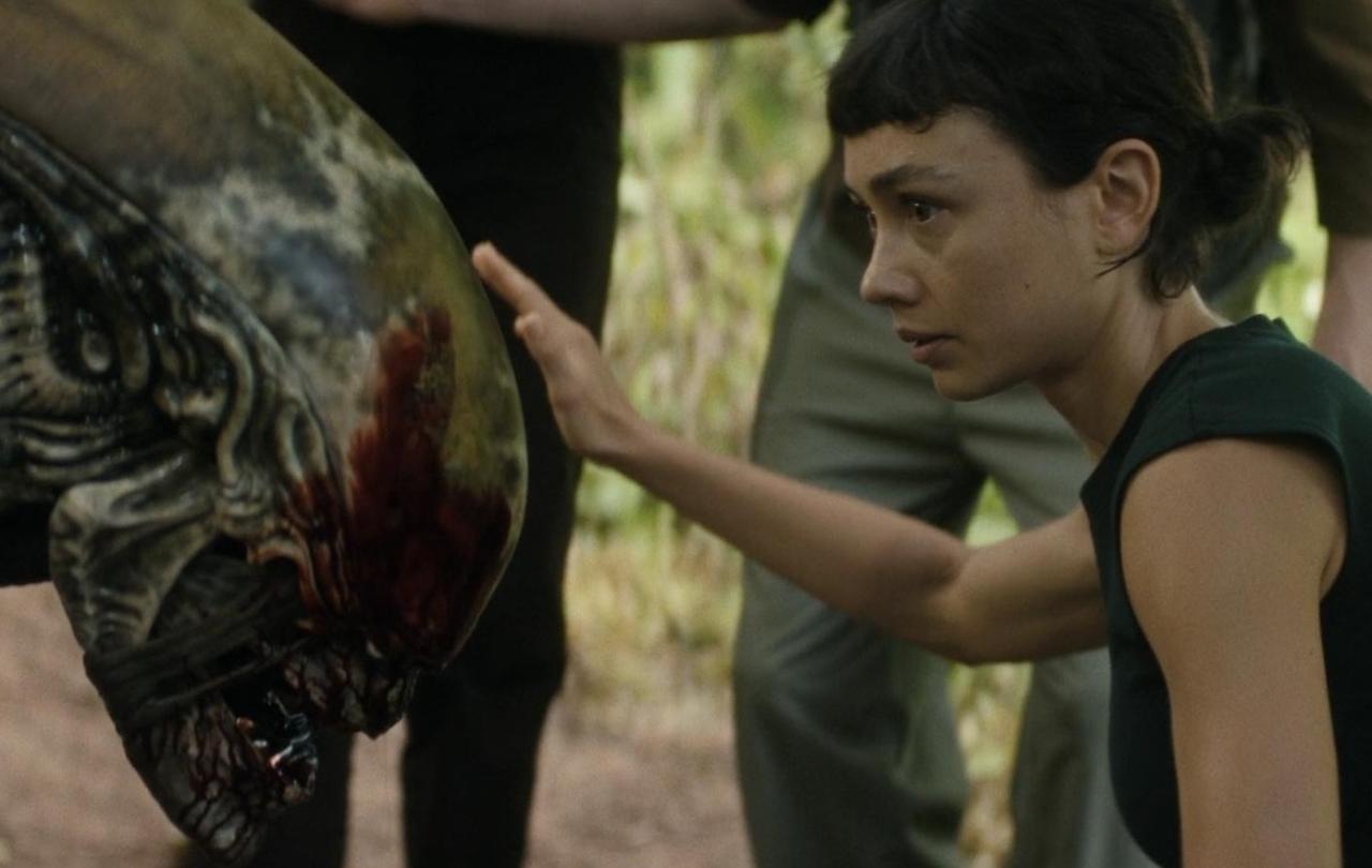 A young woman pets the head of an alien