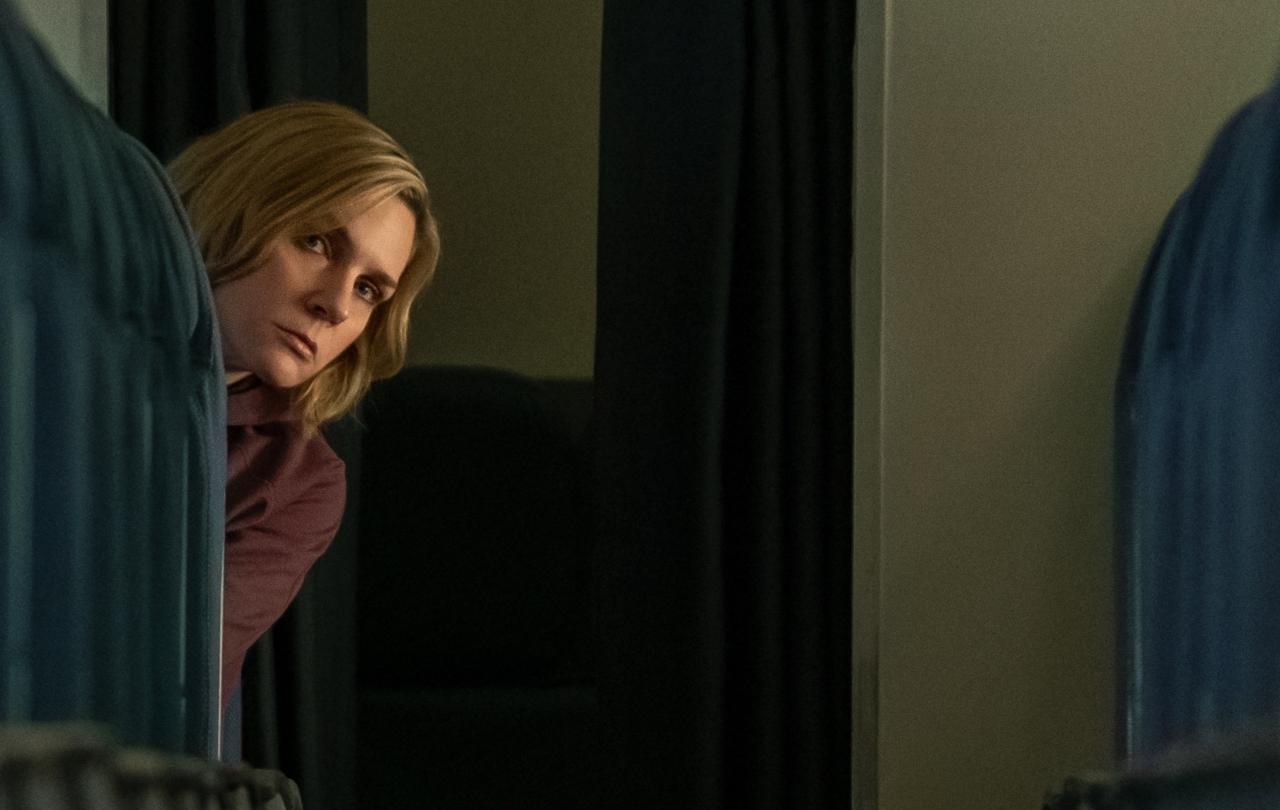 A passenger oeers out and down the aisle of an empty plane.