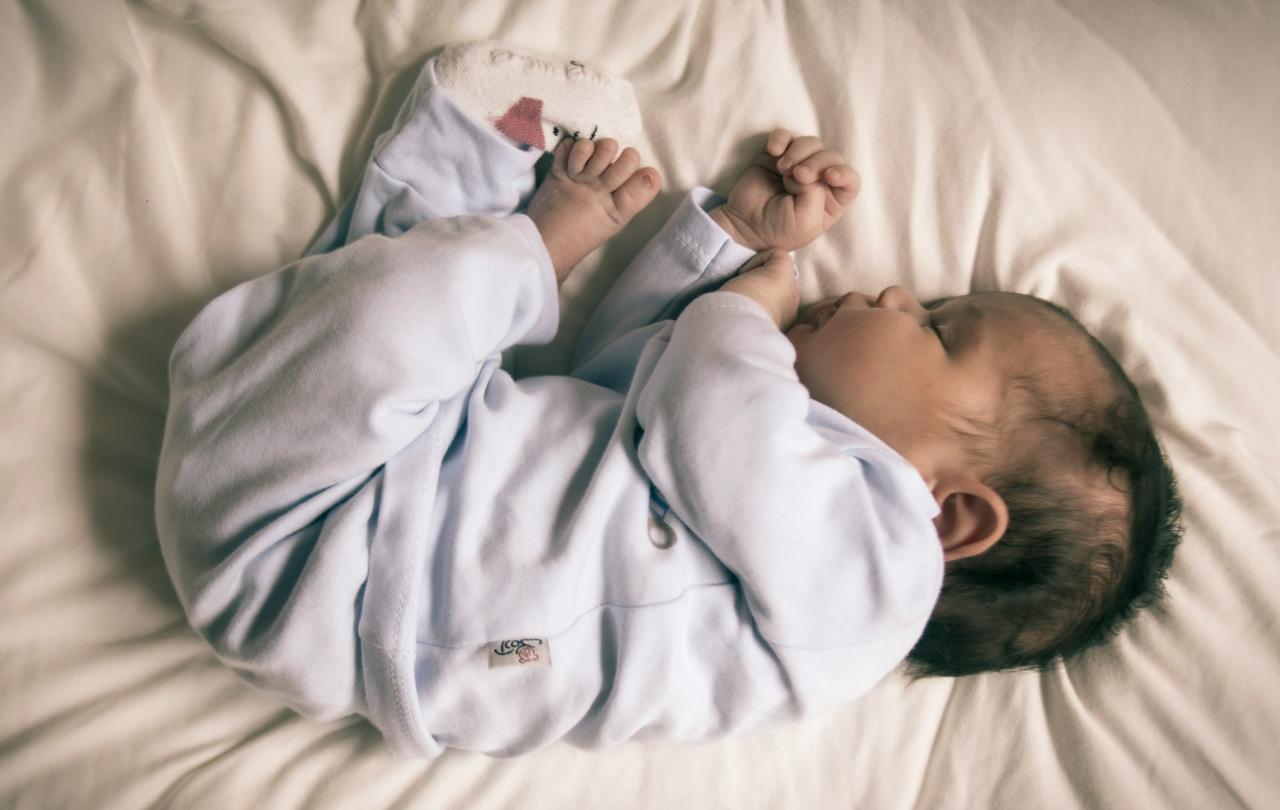 A baby sleeps curled up.