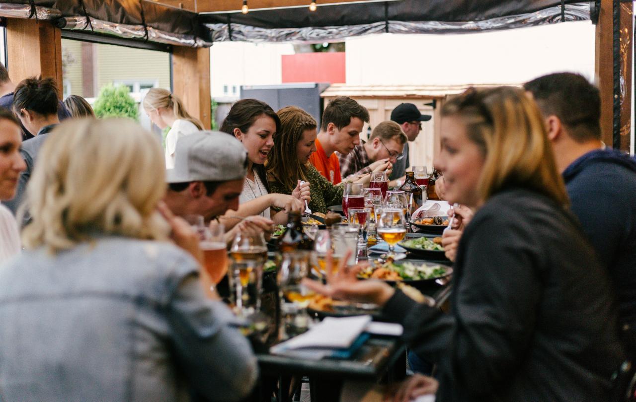 A group of friends sit arouns a large table eating together.