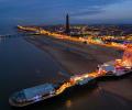 An aerial view at dusk of a brightly lit pier and promenade of the seaside town of Blackpool