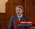 A man sits in a TV interview, below him is a captions stating 'Mark Lognan. Former Conservative MP