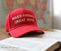 A red baseball cap, with Make America Great Again written across it, sits on an open bible.